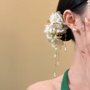 Close-up detail of an elegant cloth flower hair clip with dangling pearl tassels on a model