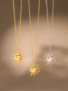 Detailed view of three metallic necklaces with personified sun pendants in gold and silver