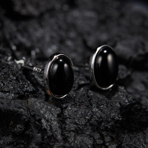Close-up of oval S925 sterling silver stud earrings with black jasper on volcanic stone