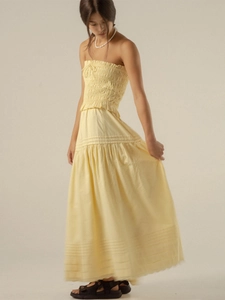 Detail of smocked strapless top and tiered light yellow maxi skirt with pleated hemline