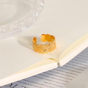 Detailed close-up of adjustable gold ring featuring embossed leaf patterns on an open book