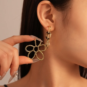 Close-up of minimalist gold hollow flower earrings on model with abstract petal design