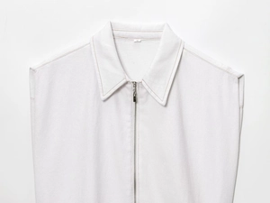 Détail d'un gilet en jean blanc avec col zippé et surpiqûres contrastées