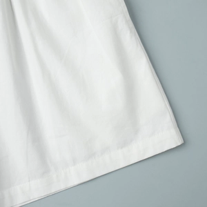 Gros plan détaillé sur la texture du tissu blanc et les coutures de précision de l'ensemble