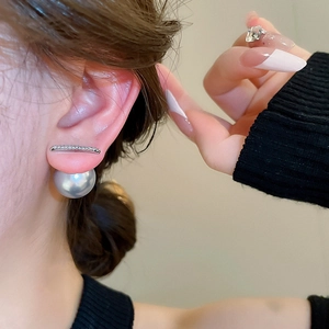 Close-up of model wearing silver zircon bar and large grey pearl earrings