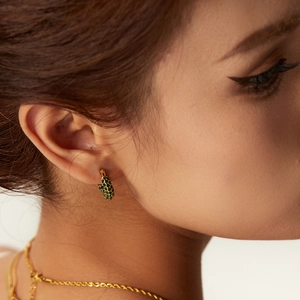 Close-up of 18k gold plated hoop earring with green stones on model's ear