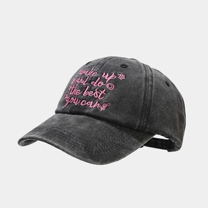 Close-up of pink embroidered text on washed charcoal grey vintage cotton baseball cap
