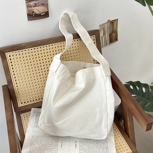 Dettaglio della borsa tote in tela beige con cuciture rinforzate su sedia vintage