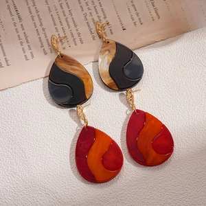 Vintage geometric teardrop earrings in irregular resin patterns on textured background