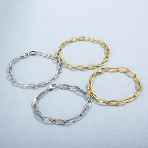 Golden and silver geometric chain bracelets with lobster clasps on a textured background