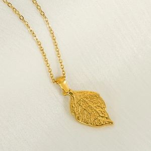Macro shot of gold leaf pendant necklace with lucky engraving on white fabric