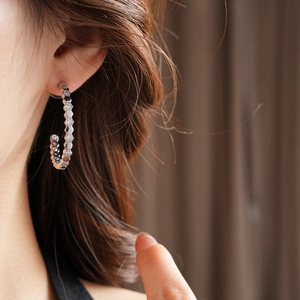 Détail macro d'une boucle d'oreille hexagonale en forme de C avec des zircons