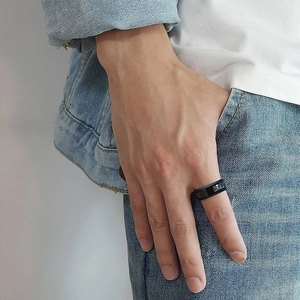 Close-up of 8mm black stainless steel men's ring worn by a model in casual style