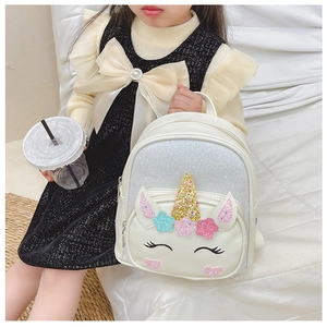 Toddler girl wearing a shiny unicorn backpack with iridescent sequins on a white background