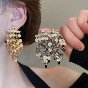 Detailed view of layered silver sequin tassel earrings worn to show movement and flow