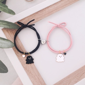 Close-up of magnetic heart clasp connecting pink and black woven ghost couple bracelets