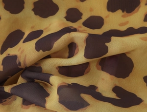 Close-up of lightweight yellow leopard print chiffon fabric with smooth texture