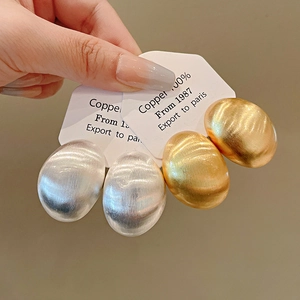 Primo piano di eleganti orecchini a perno ovali in metallo spazzolato oro e argento