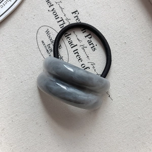 Close-up of dual grey marble texture acrylic rings on a black elastic hair tie