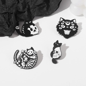 Macro detail of gothic enamel pins featuring creative skull cat motifs on black paper