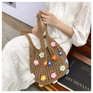 Close-up of brown knit tote bag with colorful crochet flower patterns on a wooden bench
