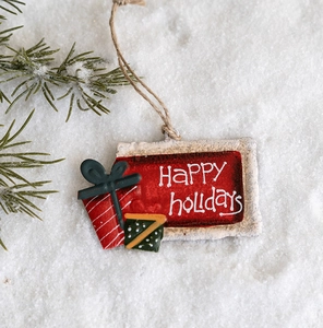 Close-up of vintage iron Christmas tags with Happy Holidays text on snowy pine background