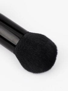 Macro shot of dense black synthetic bristles on a dual-ended makeup brush with a sleek handle