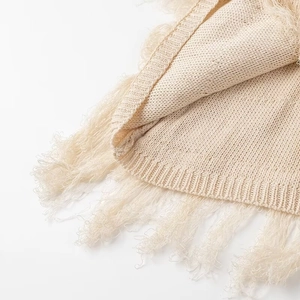 Détail de la robe en maille crème avec bordure à franges et texture de tricotage
