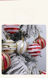 Close-up of red and white striped Christmas ornaments hanging on a snowy tree branch