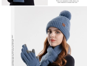 Close-up of blue knit hat, scarf, and touch screen gloves with faux fur pom-pom detail