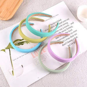 Cinq serre-têtes en éponge aux couleurs pastel disposés sur un magazine au style minimaliste
