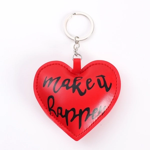Close-up of red heart leather keychain with silver ring and 'make it happen' text