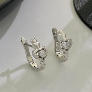 Detail of silver heart-shaped earrings with zircon inlay and snap-lock closure