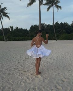 Detail of the backless white dress featuring crisscross straps and tiered ruffle hem