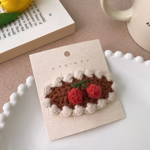 Vue macro d'une barrette faite main en tricot avec cerises brodées et bordure en dentelle