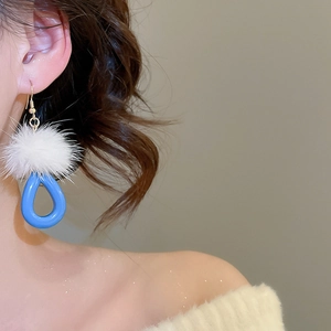 Close-up of white plush ball and blue water-drop pendant earring on female model