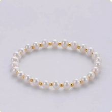 Macro detail of natural freshwater pearls with golden metallic beads on a minimalist bracelet