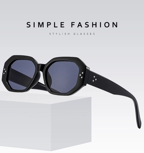 Macro shot of black thick-frame polygonal sunglasses displayed on a geometric white pedestal