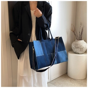 Close-up of a blue patchwork denim tote bag with durable metal buckles and handles