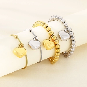 Dettaglio di bracciali a strati con perline e cuore in oro 18K e argento su supporto