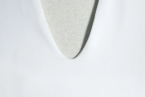 Detailed macro view of high-quality white knitted fabric with clean stitching on the neckline
