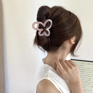 Detail of pink butterfly hair claw clip with hollow design on a stylish bun hairstyle