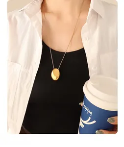 Close-up of minimalist oval gold-plated pendant necklace on a model with white shirt