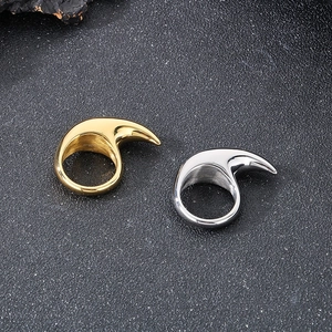 Detail shot of silver and gold crescent moon stainless steel rings on a dark surface