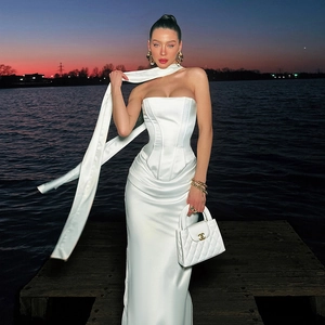 Elegante completo da sera in raso bianco con top a corsetto e gonna lunga al tramonto al molo