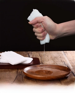 Detailed shot of soft white disposable towel being wrung out showing high water absorption