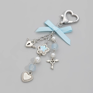 Detail view of blue ribbon bow keychain with silver winged heart lock and pearl beads