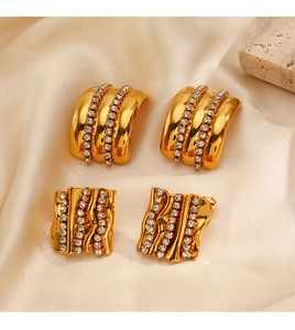 Gros plan de boucles d'oreilles dorées avec zircon sur soie beige et pierre décor