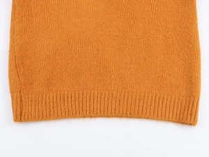 Détail du pull en maille jaune moutarde montrant l'ourlet côtelé et la texture douce