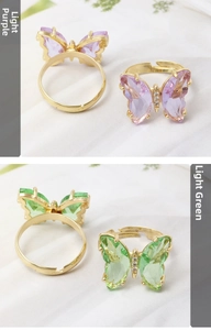 Close-up of adjustable butterfly rings in light purple and green crystal with gold band